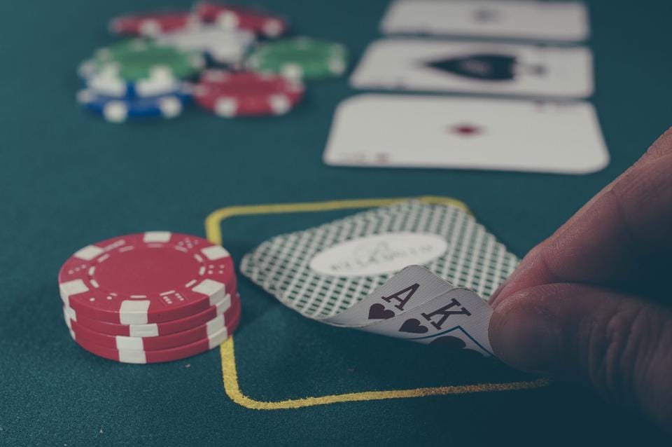 Playing cards and stacked poker chips on a green felt table.