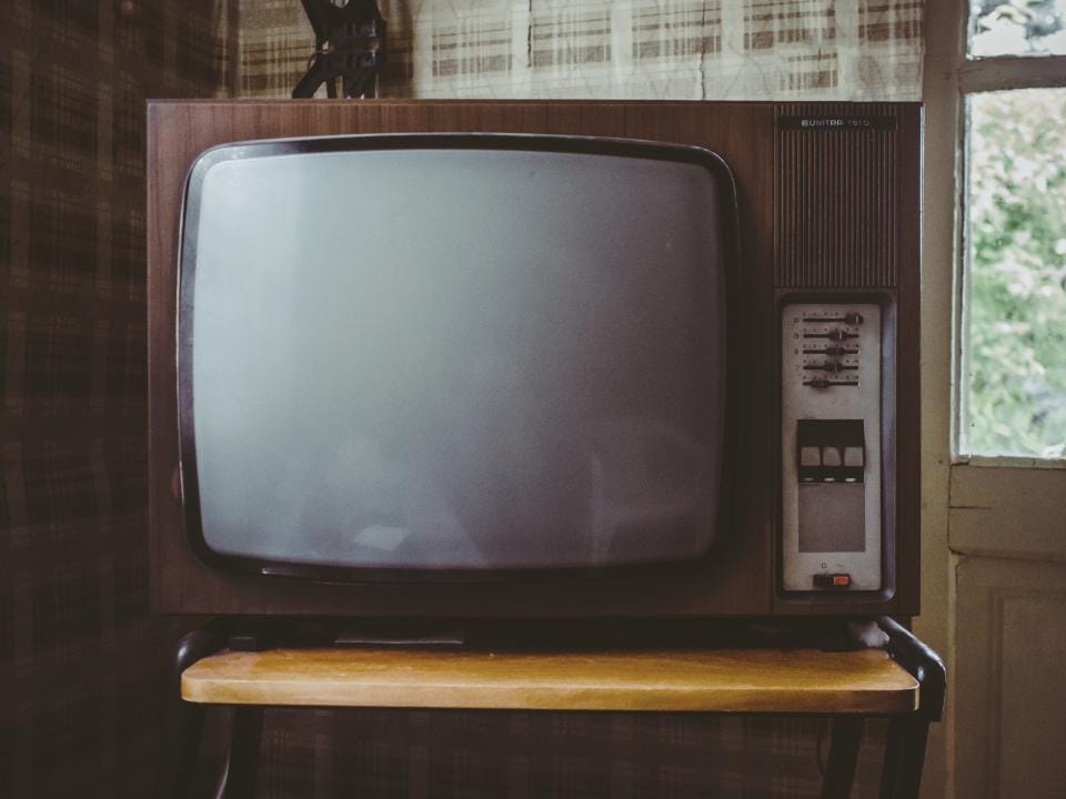 A vintage wood-cased television set resting on a wooden stand.