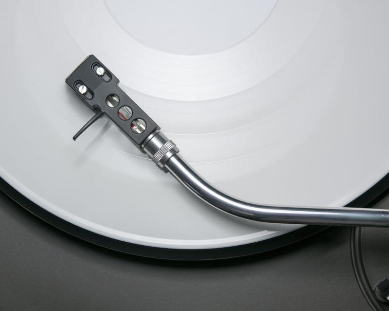 A record spinning on a turntable with the tonearm resting on a white vinyl disc.