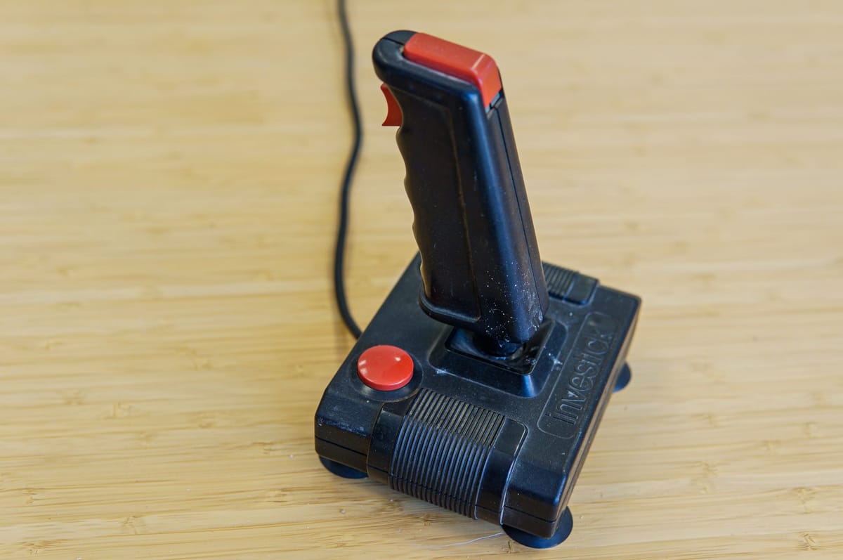A retro black arcade joystick with a red fire button.